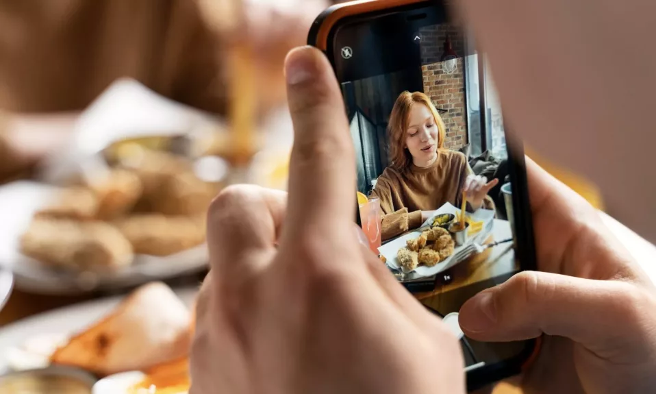Person taking photo of woman dining